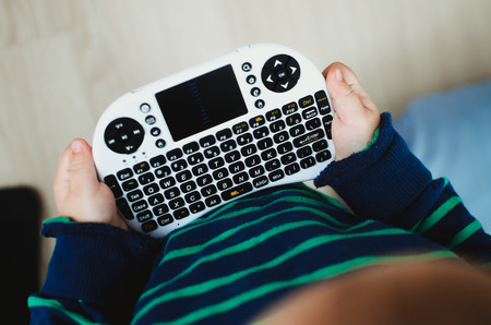 the child is playing, is dealing with a mini-keyboard for computer equipment