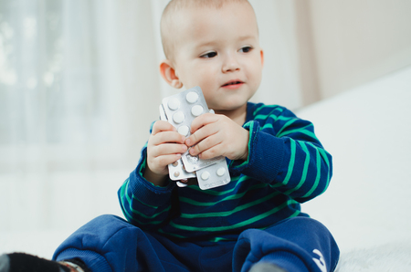 The child plays with the pills on the bedの写真素材