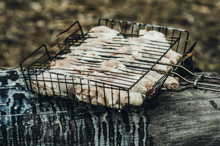 Raw meat in the grid lies on a log, marinated with mayonnaise and seasoningsの写真素材