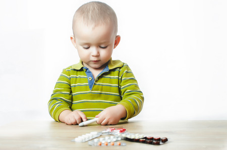 the child Holds the thermometer in hands on a white isolated backgroundの写真素材