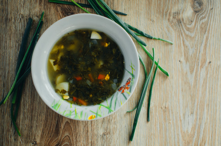 Soup with sorrel on wooden table in rustic style