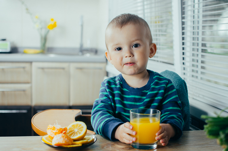 baby in the kitchen drinking orange juice, vitamins and healthの写真素材