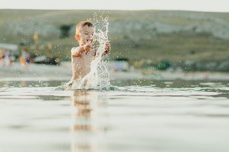 Happy baby playing in the sea, splashing, rejoicing, littleの写真素材