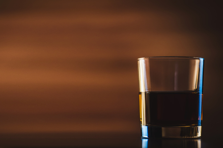 Scotch on wooden background with copyspace. An old and vintage countertop with highlight and a glass of hard liquorの写真素材