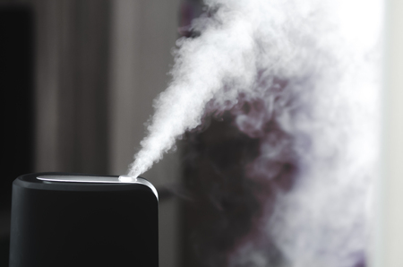 The steam from the humidifier at night in the dark blackの写真素材
