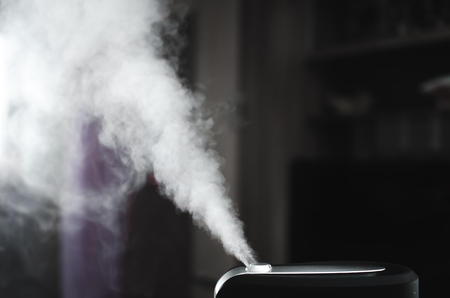 The steam from the humidifier at night in the dark blackの写真素材