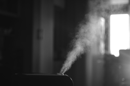 The steam from the humidifier at night in the dark blackの写真素材