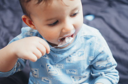 Baby eating cottage cheese before bed in the bedroom, in my pajamasの写真素材
