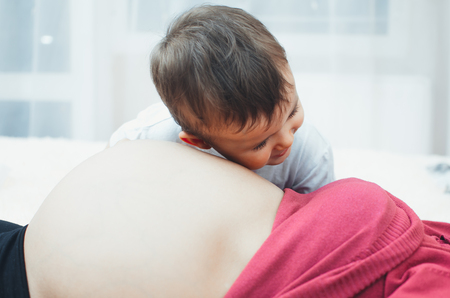 the child listens to the belly of a pregnant womanの写真素材