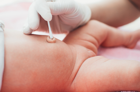 Mom or a doctor wearing gloves to handle the navel baby girlの写真素材