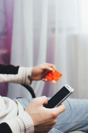 men hands, holding the phone and a visa card or another, entering data from the cardの写真素材