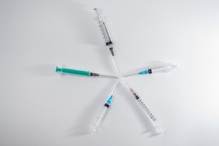 Syringes on white in different sizes, and containers for medications and insulinの写真素材