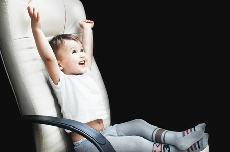 Child in a chair, in a white t-shirt is very happy about the win or the goal, place for inscriptionの写真素材