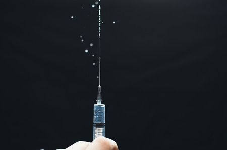 Syringe with medication in hand on black backgroundの写真素材