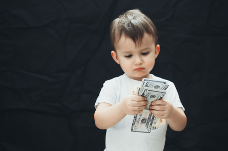 the child with the money in the hands folded on black backgroundの写真素材