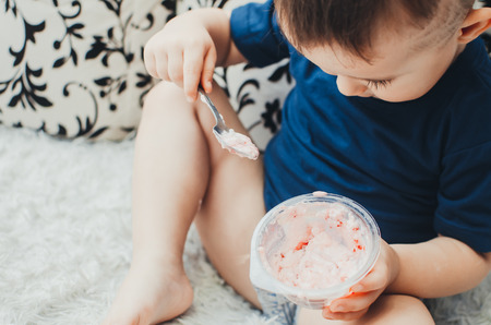baby boy sitting on the couch in your underwear eating yogurt in the comfort of homeの写真素材