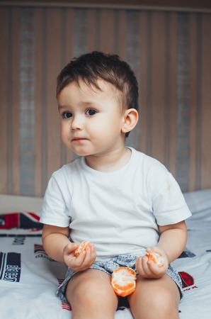 the child at home, at home eating Mandarin wedges, very happyの写真素材