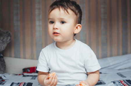 the child at home, at home eating Mandarin wedges, very happyの写真素材