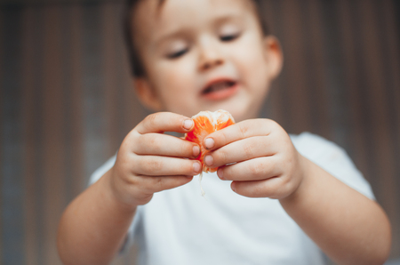 the child at home, at home eating Mandarin wedges, very happyの写真素材