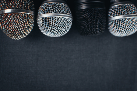 Gray on the table are microphones next to the remote, all on a black backgroundの写真素材