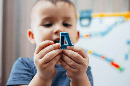 the little boy is studying the letters, using the easel with a magnetic surfaceの写真素材