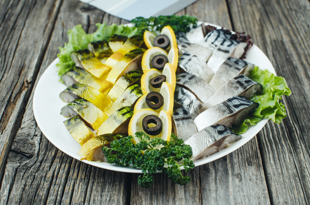 on the old wooden table beautifully on the plate is a mackerel and herring decoratedの写真素材