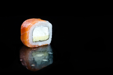Sushi or rolls with Philadelphia cheese and tobiko on black background with reflection.の写真素材