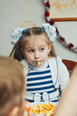 baby girl eating French fries with her hands at the birthday party greedilyの写真素材