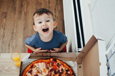 baby next to big pizza in the kitchen, very surprised by the sizeの写真素材