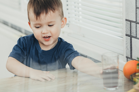 charming baby in the kitchen in the summer drink of pomegranate or cherry juice red colorの写真素材