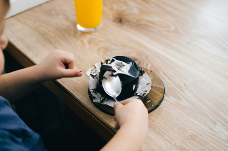 A small child eats a black chocolate cake, at home in the kitchenの写真素材