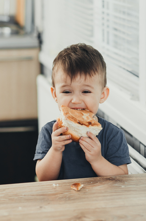 the child in the kitchen eating a sweet bun, very tastyの写真素材