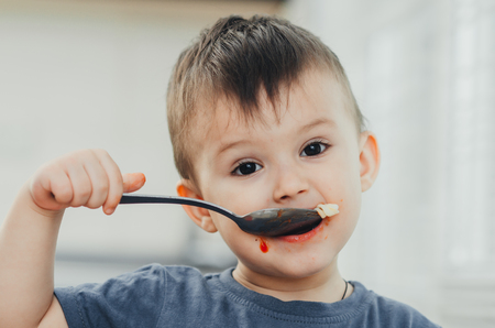 little baby boy in the kitchen eating pasta with cutlets, very tastyの写真素材