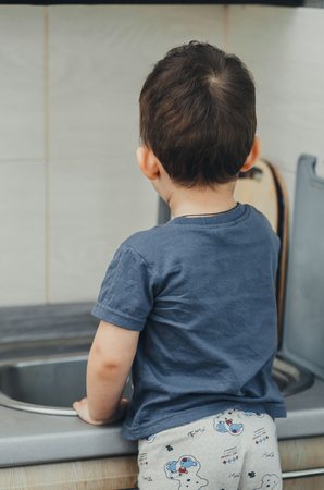 The little boy washes his hands under the crane on his ownの写真素材