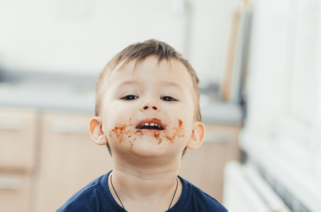 Charming child portrait, dirty face in chocolate or condensed milkの写真素材