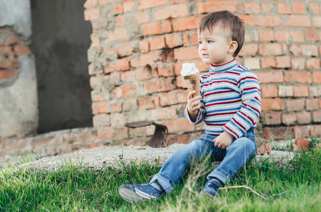 little cute boy   eating ice cream  on brick wall background