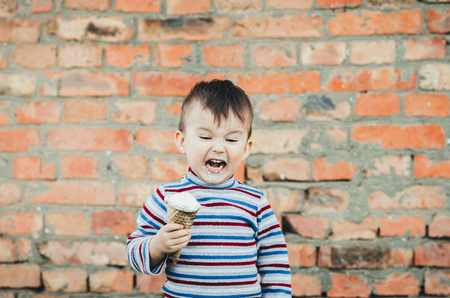 little cute boy eating ice cream three years very appetizing, amid nature, green grassの写真素材