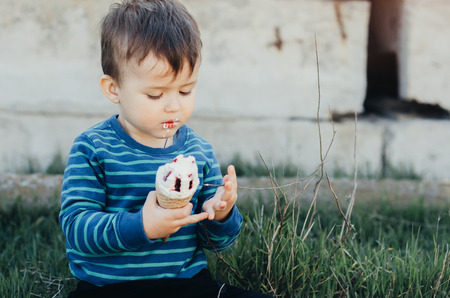 Baby eating ice cream outdoors, in abandoned places, outside the house grunge style