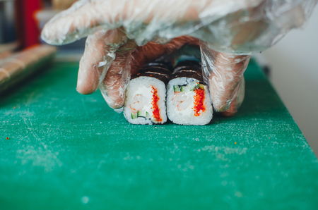 The cook makes a sushi roll with bamboo Mat cuts. The process of cooking sushi rollの写真素材
