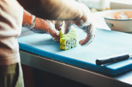 The cook makes a sushi roll with bamboo Mat cuts. The process of cooking sushi rollの写真素材