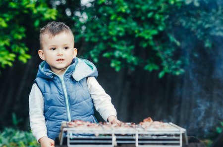 a small child on their own barbecue on the grill helpsの写真素材