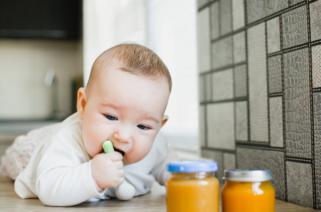 beautiful baby with blue eyes wants fruit puree pumpkin apricot Apple and peachの写真素材