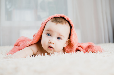 Baby after shower in pink or peach towel on headの写真素材
