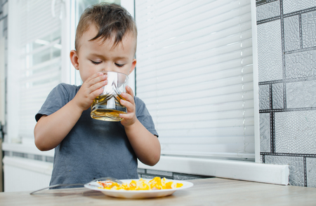 child in the kitchen drinking Apple juice and eating omeletの写真素材