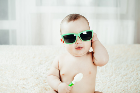 Portrait of a little girl in sunglasses with a spoon in her handの写真素材