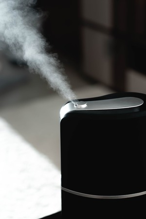 The steam from the humidifier at night in the dark blackの写真素材