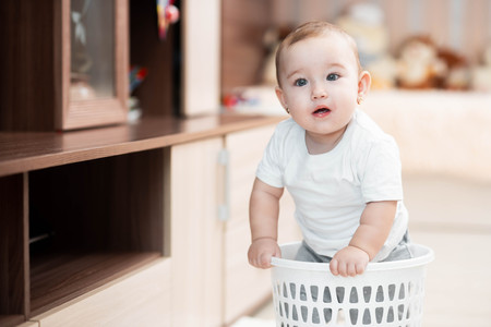 Little kid sitting in an office trash can, girlの写真素材