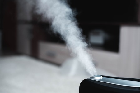 The steam from the humidifier at night in the dark blackの写真素材