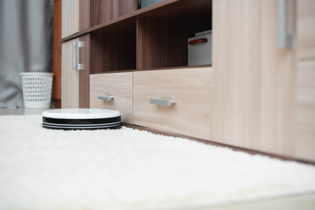 New white clean robot vacuum cleaner on laminate floor and carpetの写真素材
