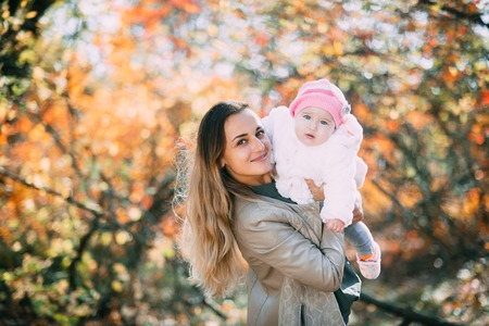 Charming child in the arms of his mother in the autumn forestの写真素材